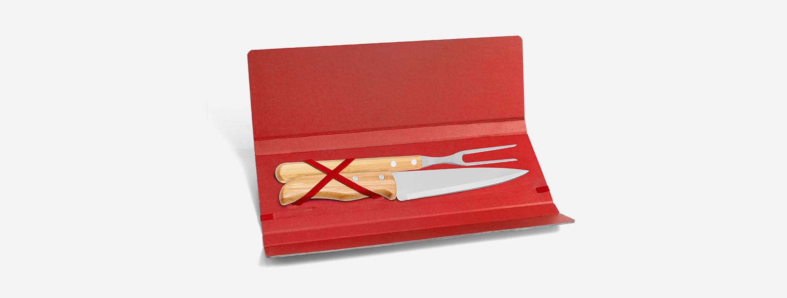 Conjunto composto por uma faca 7” e um garfo trinchante, ambos com cabos em Bambu e lâminas em Aço Inox com rebites resistentes. Estão organizados em uma pasta vermelha com elásticos.